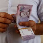 A person holding a stack of banknotes, depicting financial transactions.